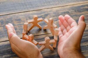 business success concept wooden table top view hands protecting wooden figures people 65516d81110fce114130f343