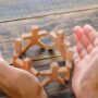 business success concept wooden table top view hands protecting wooden figures people 65516d81110fce114130f343