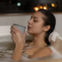 young woman drinking coffee relaxing while taking bath