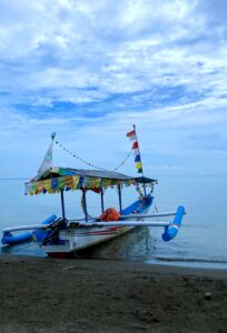 a boat on the beach water with blue sky and clouds in the background