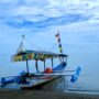 a boat on the beach water with blue sky and clouds in the background