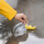 boy playing water with paper boat close up