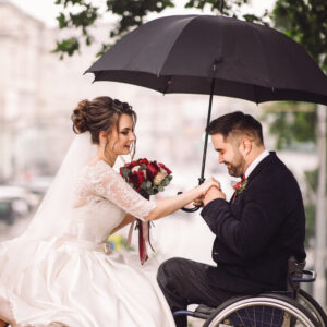 bride and groom on the wheelchair sit kissing on the bench in th